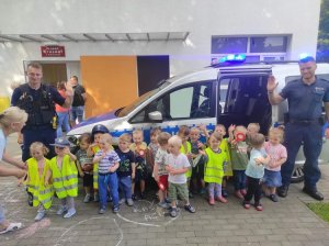 dwóch policjantów, radiowóz policyjny, grupa małych dzieci