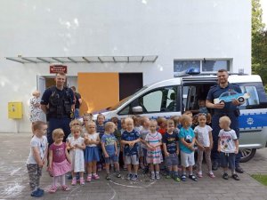 dwóch policjantów, radiowóz policyjny, grupa małych dzieci