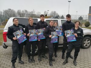 7 uczniów ubranych w czarne mundury z plakatami pt. zostań policjantem