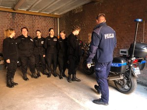 sześciu uczniów i umundurowany policjant w garażu przy policyjnym motocyklu