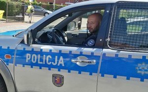 mł. asp. Rafał Traut siedzący w policyjnym oznakowanym radiowozie na ulicy
