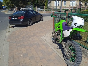 czarne auto osobowe i zielony motocykl na drodze