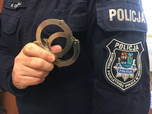 umundurowany funkcjonariusz policji trzymajacy kajdanki