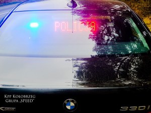 Tył czarnego pojazdu m-ki BMW, napis na tylnej szybie POLICJA