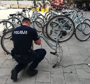 umundurowany policjant znakujący rower, w tle rowery