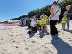 umundurowany policjant rozmawiający z grupką dzieci na plaży i chodniku