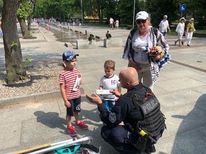 umundurowany policjant rozmawiający z grupką dzieci na plaży i chodniku