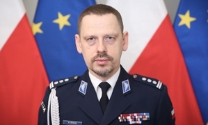 umundurowany policjant - komendant KGP na tle flag Polski i UE