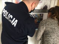 kobieta i umundurowany policjant wieszają plakat dotyczący wstąpienia do policji