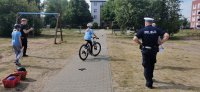 umundurowany policjant, dziecko na rowerze