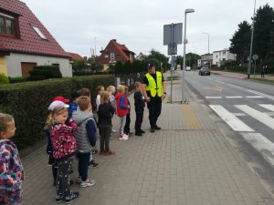 Umundurowany policjant wraz z grupką dzieci na chodniku