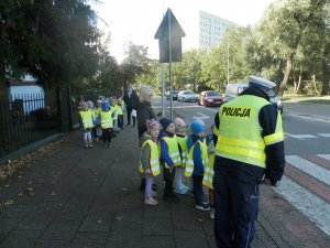 umundurowany policjant z gromadką dzieci na przejściu dla pieszych