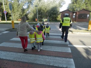 umundurowany policjant z gromadką dzieci na przejściu dla pieszych