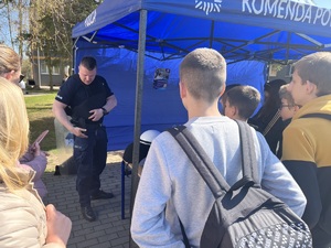 policjant pokazujący młodzieży jak prawidłowo zakładać kamizelkę kuloodporną