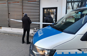 oznakowany radiowóz policji, policjant w cywilnych ciuchach przed sklepem spożywczym