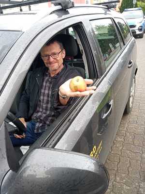 kierujący w pojeździe osobowym trzymający jabłko