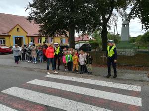umundurowane funkcjonariuszki z gromadką dzieci na przejściu dla pieszych i przy przedszkolu