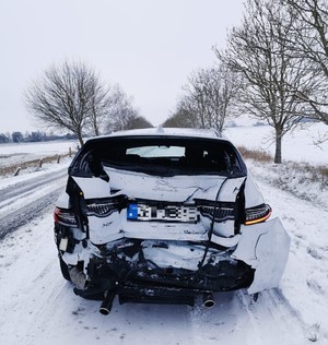 uszkodzony tył białego pojazdu osobowego na drodze pokrytej śniegiem