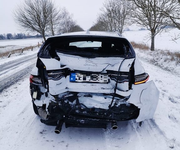 uszkodzony tył białego pojazdu osobowego na drodze pokrytej śniegiem