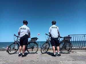 umundurowani policjanci, rowery na tle nieba i morza