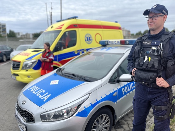 Akcja #Bezpieczniiświadomi, umundurowani policjanci, umundurowani ratownicy medyczni, policyjny radiowóz, ambulans
