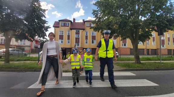 grupa dzieci, pojazdy, przejście dla pieszych, umundurowani policjanci