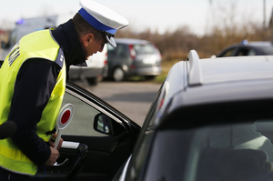 umundurowany policjant nachylający się na pojazdem osobowym