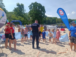 plaża, umundurowani funkcjonariusze, grupa dzieci i dorosłych