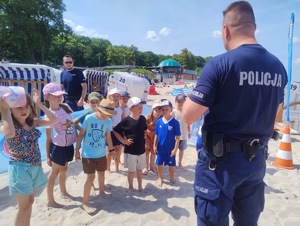 plaża, umundurowani funkcjonariusze, grupa dzieci i dorosłych