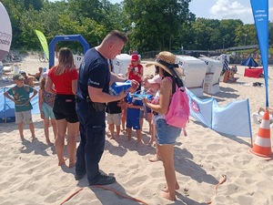 plaża, umundurowani funkcjonariusze, grupa dzieci i dorosłych