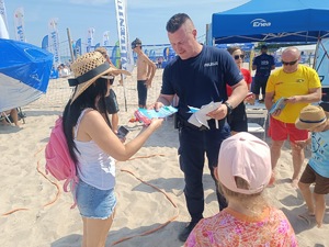 plaża, umundurowani funkcjonariusze, grupa dzieci i dorosłych