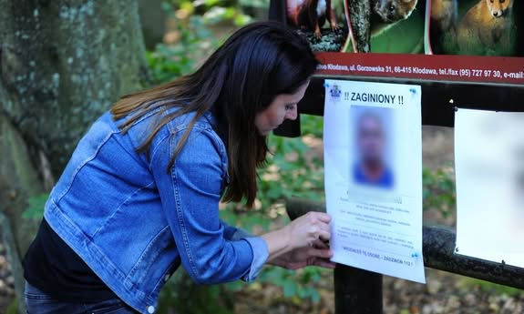 kobieta nachylająca się nad plakatem przedstawiającym mężczyznę